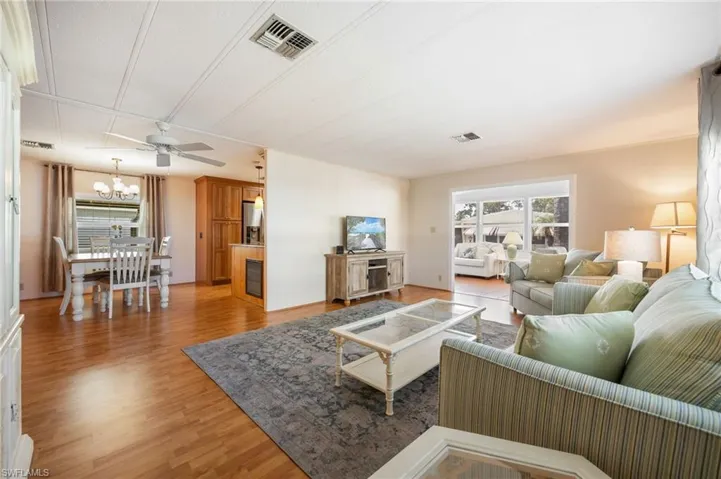 Living area with light wood finished floors, ceiling fan, and hanging lights