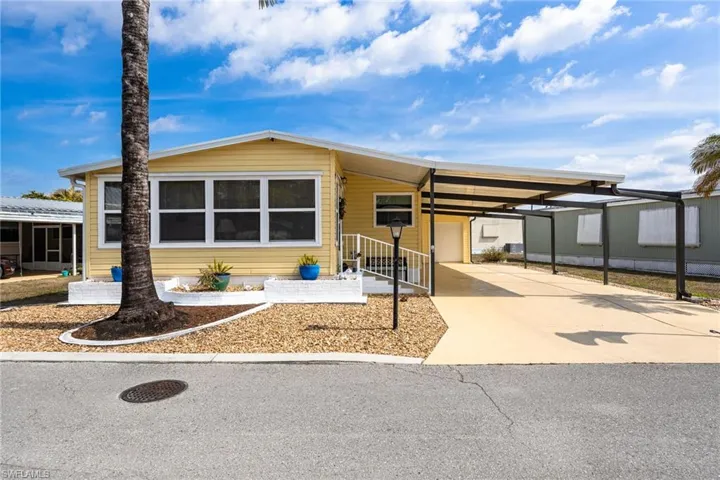 Manufactured / mobile home featuring a carport and driveway