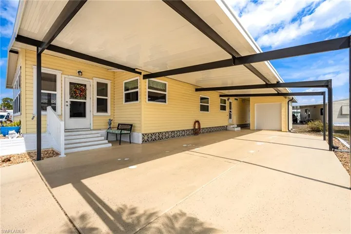 View of front of property with entry steps, a carport, and a patio