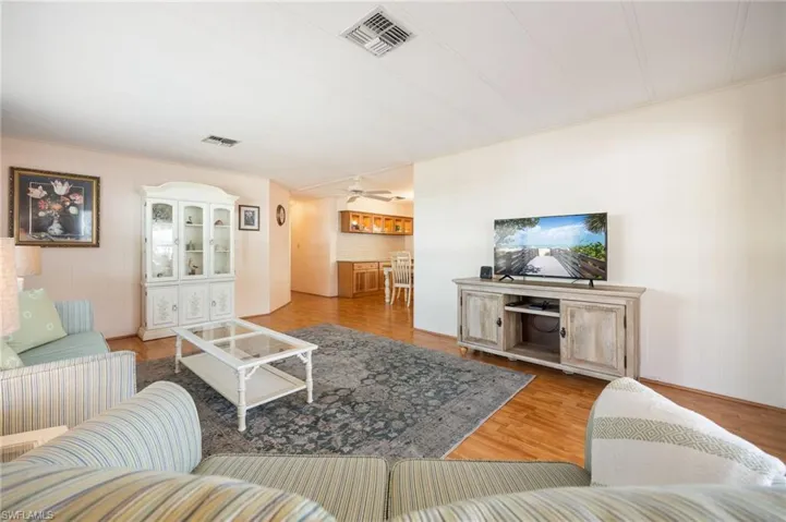 Living room featuring crown molding, wood finished floors, and a ceiling fan