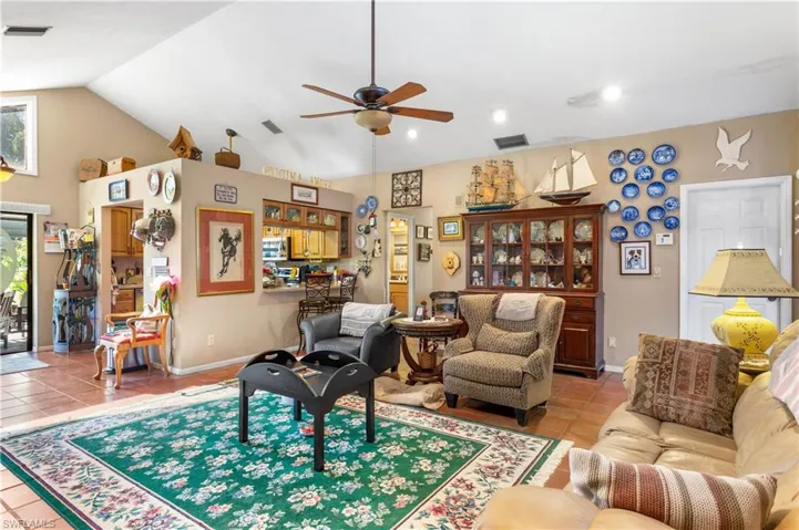 Living room with tile flooring, ceiling fan, and lofted ceiling
