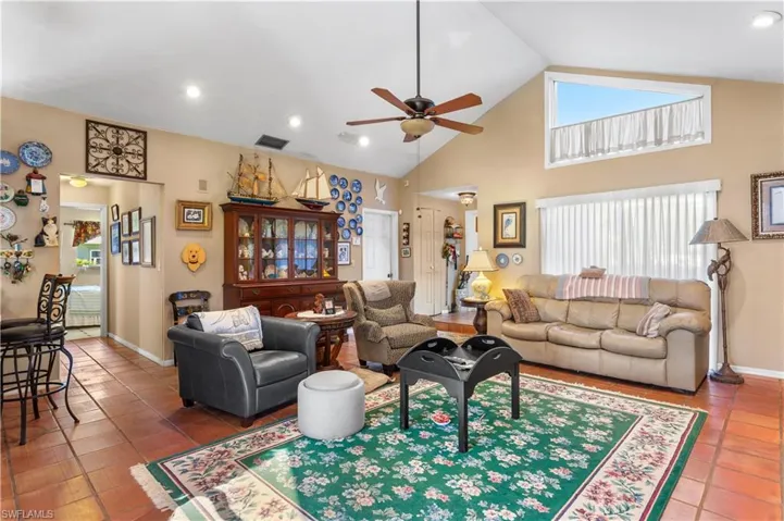 Living room with high vaulted ceiling, ceiling fan, and tile floors