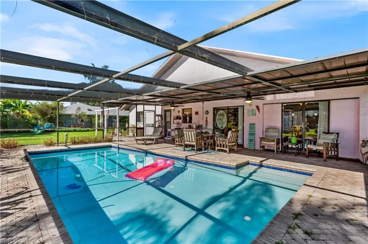 View of pool featuring a patio and glass enclosure