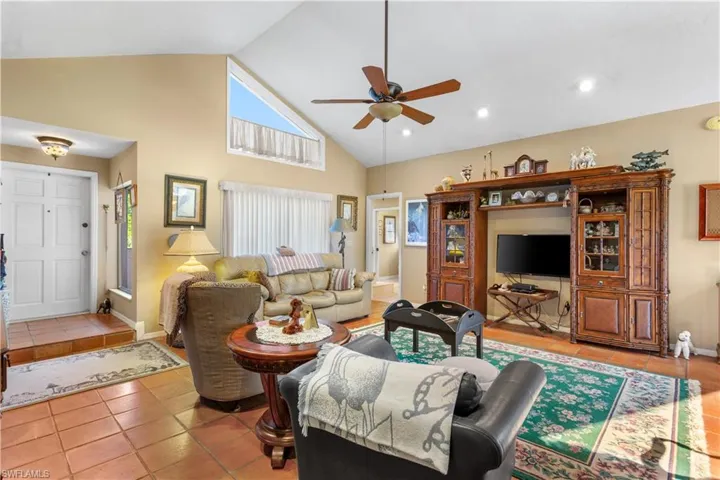 Living room featuring high vaulted ceiling, ceiling fan, and light tile floors