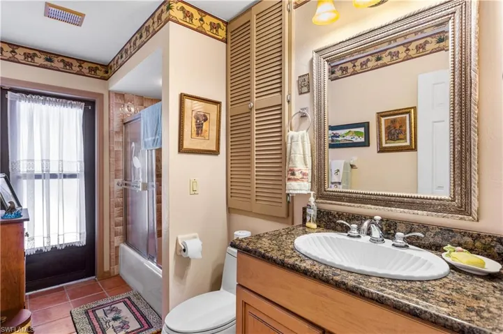 Full bathroom with enclosed tub / shower combo, tile flooring, oversized vanity, and toilet