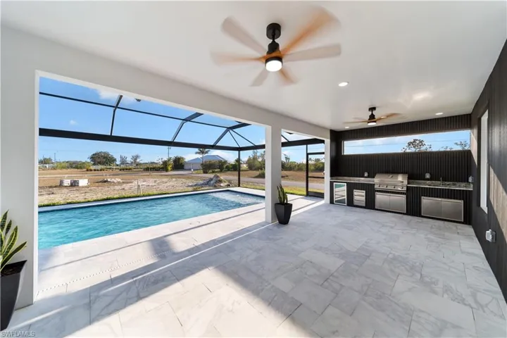 Outdoor pool featuring a patio area, a ceiling fan, a grill, a lanai, and exterior kitchen