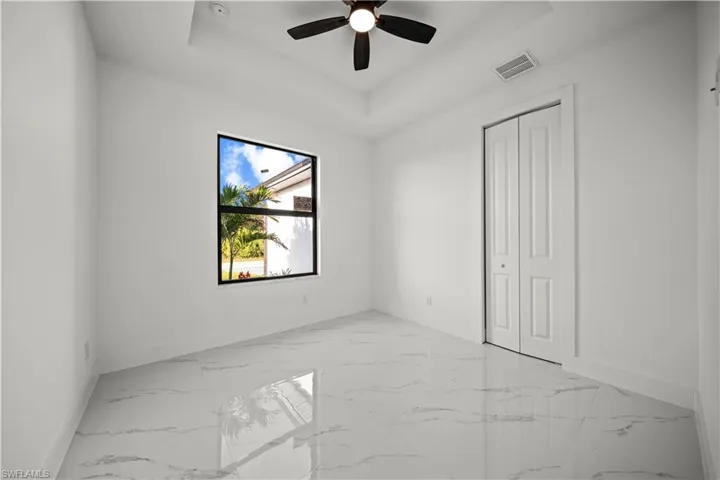 Unfurnished room featuring a tray ceiling, baseboards, ceiling fan, and visible vents
