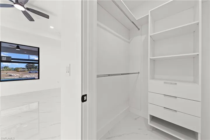 Walk in closet with marble finish floor and ceiling fan