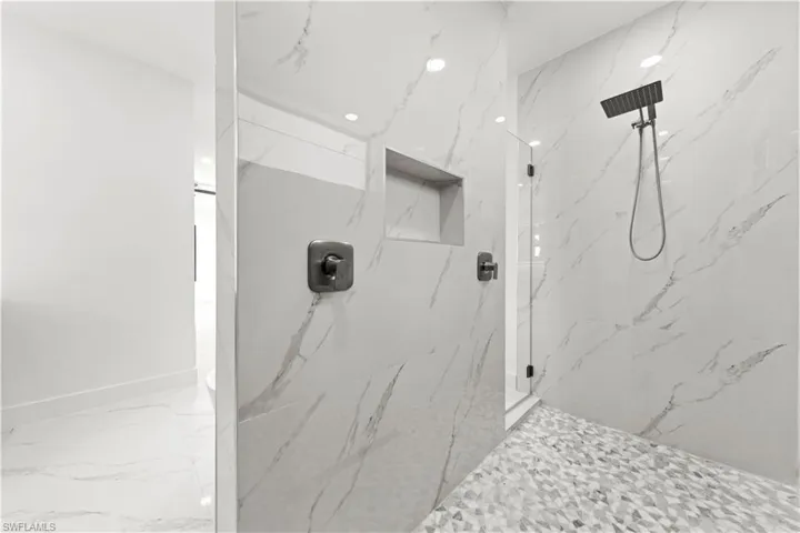 Full bathroom with marble finish floor, a marble finish shower, and baseboards