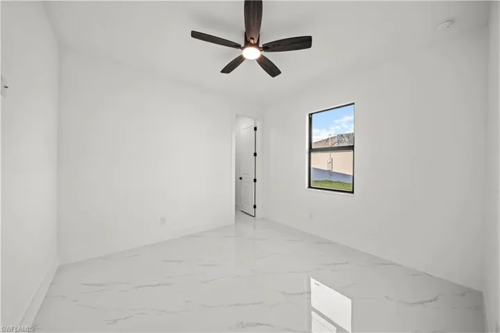 Unfurnished room with marble finish floor, baseboards, and ceiling fan