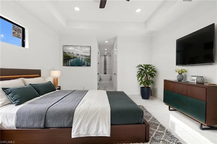 Bedroom featuring a raised ceiling, recessed lighting, and marble finish floor