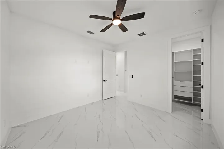 Unfurnished bedroom with baseboards, visible vents, and a walk in closet