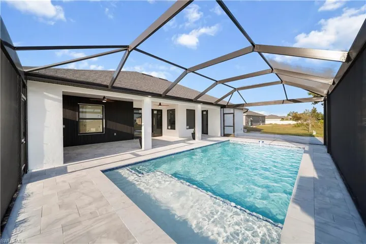 Pool featuring glass enclosure, ceiling fan, and a patio area
