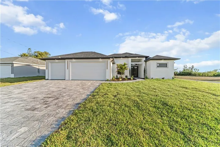 Prairie-style home with stucco siding, decorative driveway, a front lawn, and an attached garage
