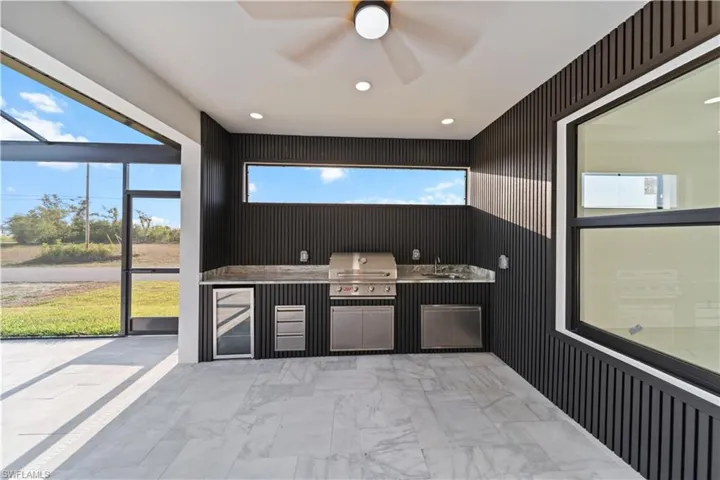 Kitchen with wine cooler, a sink, a ceiling fan, marble finish floor, and recessed lighting