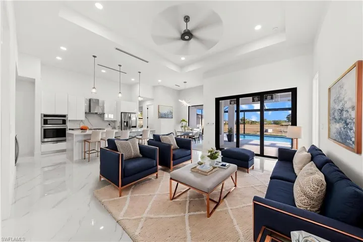 Living area with recessed lighting, marble finish floor, a towering ceiling, and ceiling fan