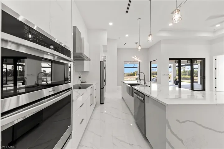 Kitchen featuring a wealth of natural light, modern cabinets, stainless steel appliances, wall chimney range hood, and white cabinets