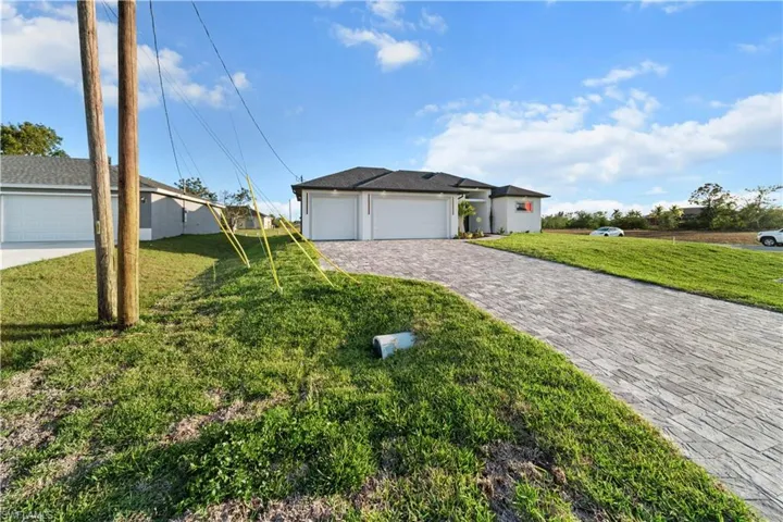 View of front of property with a front yard, decorative driveway, and stucco siding