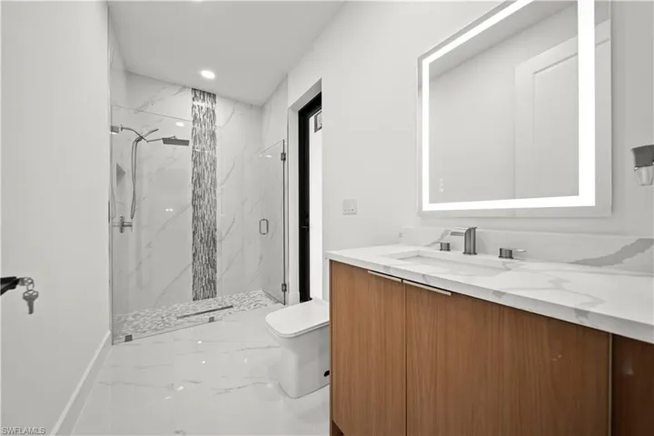 Bathroom featuring toilet, vanity, a marble finish shower, marble finish floor, and recessed lighting