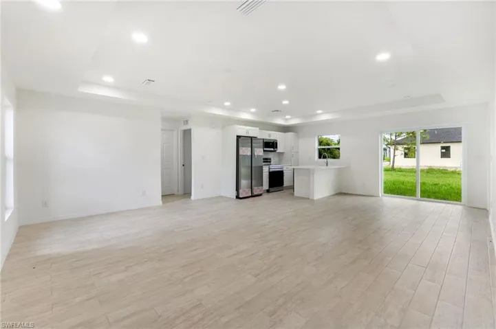 Unfurnished living room with a raised ceiling, light hardwood / wood-style floors, and sink