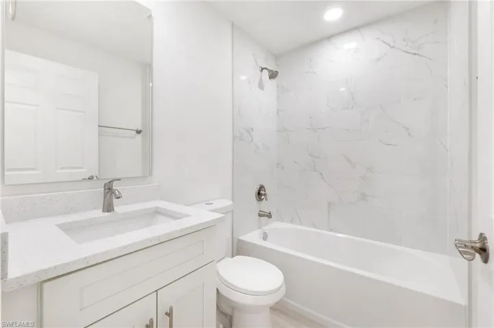 Full bathroom featuring tiled shower / bath combo, vanity, and toilet