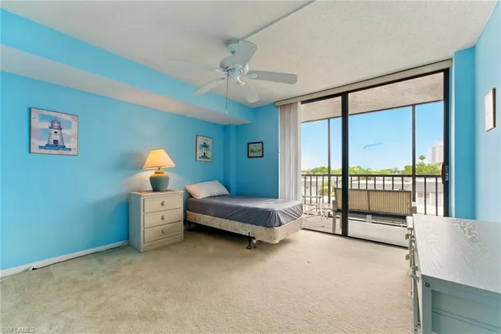 Bedroom featuring light carpet, access to exterior, expansive windows, ceiling fan, and a textured ceiling