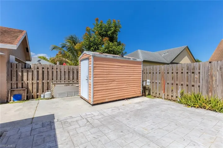 View of patio featuring fence, an outdoor structure, and a shed