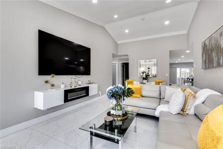 Living area featuring baseboards, marble finish floor, recessed lighting, and ornamental molding