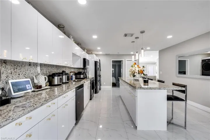 Kitchen featuring marble finish floor, visible vents, modern cabinets, baseboards, and black appliances
