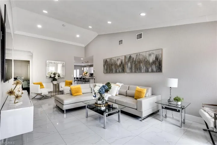 Living area featuring vaulted ceiling, visible vents, recessed lighting, marble finish floor, and crown molding