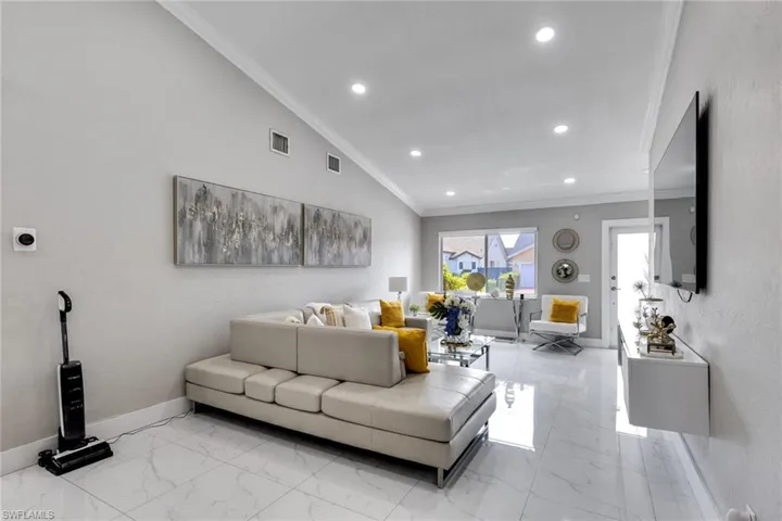 Living area with marble finish floor, baseboards, ornamental molding, and visible vents