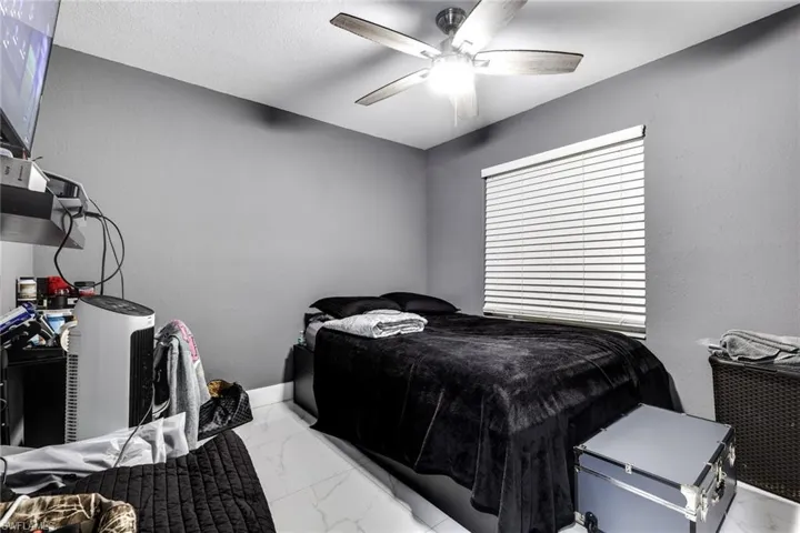 Bedroom with marble finish floor, baseboards, and ceiling fan