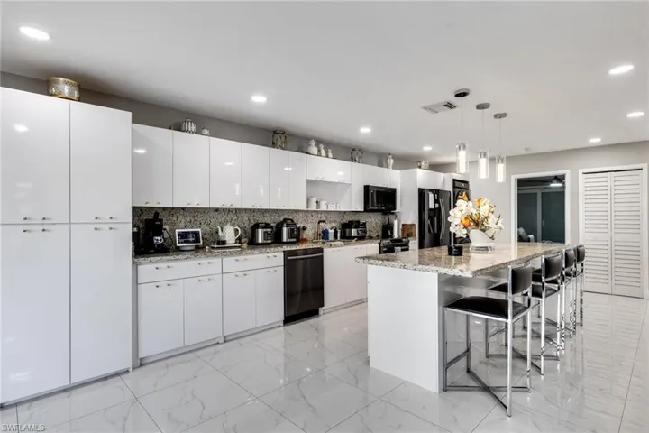 Kitchen featuring tasteful backsplash, dishwashing machine, freestanding refrigerator, visible vents, and recessed lighting