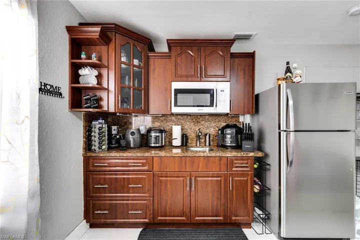 Kitchen featuring visible vents, a sink, freestanding refrigerator, white microwave, and decorative backsplash