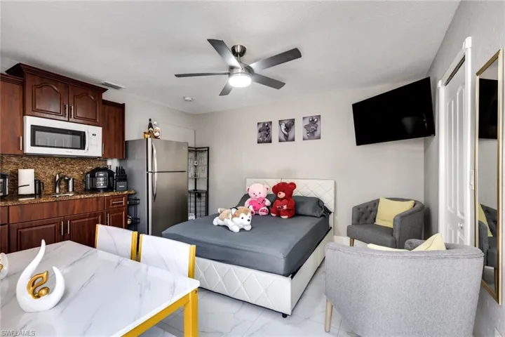 Bedroom featuring visible vents, a ceiling fan, freestanding refrigerator, and marble finish floor
