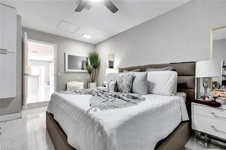 Bedroom featuring attic access, marble finish floor, visible vents, and ceiling fan