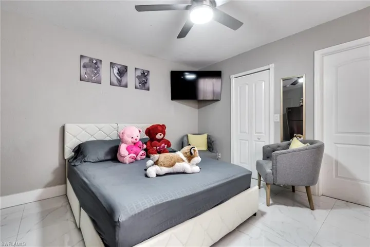 Bedroom featuring marble finish floor, a ceiling fan, freestanding refrigerator, a closet, and baseboards