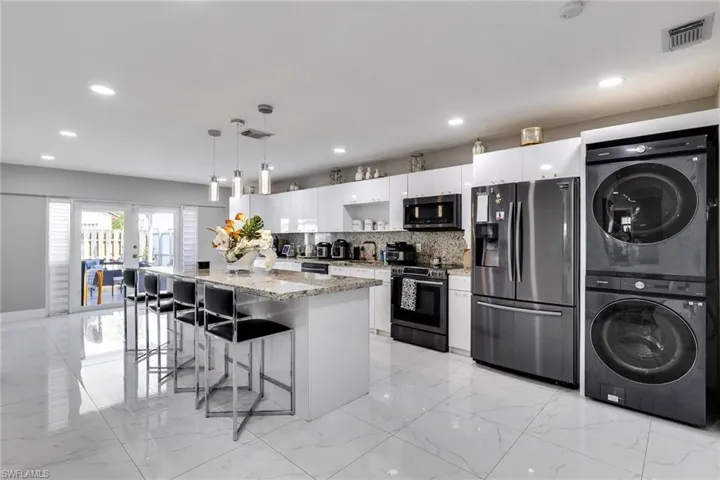 Kitchen with visible vents, stacked washing maching and dryer, marble finish floor, and appliances with stainless steel finishes