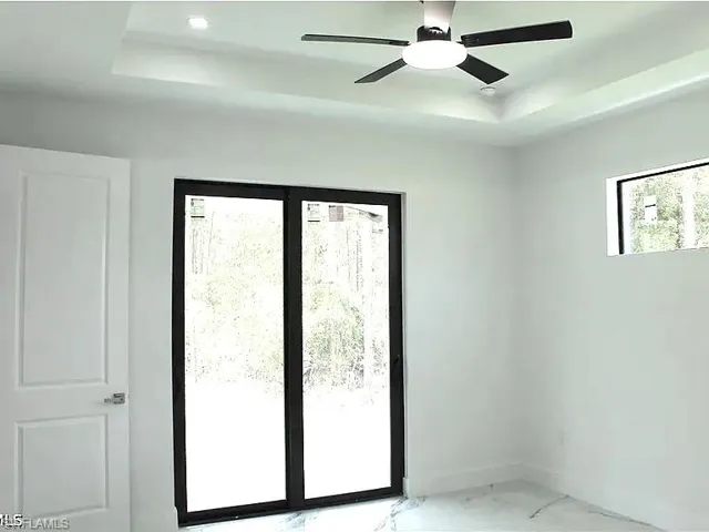 Room featuring a tray ceiling, recessed lighting, and a contemporary ceiling fan