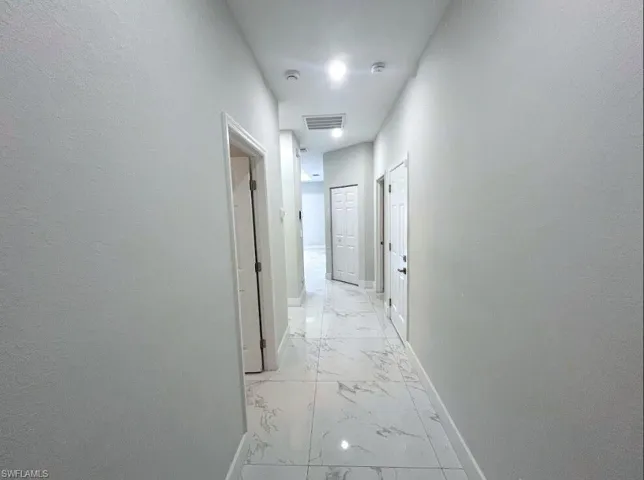Corridor featuring baseboards and light marble finish flooring
