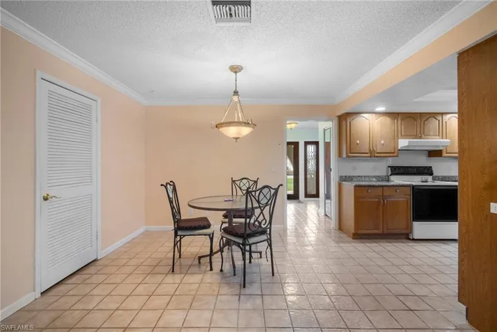 Dining area featuring a textured ceiling, light tile patterned floors, and crown molding