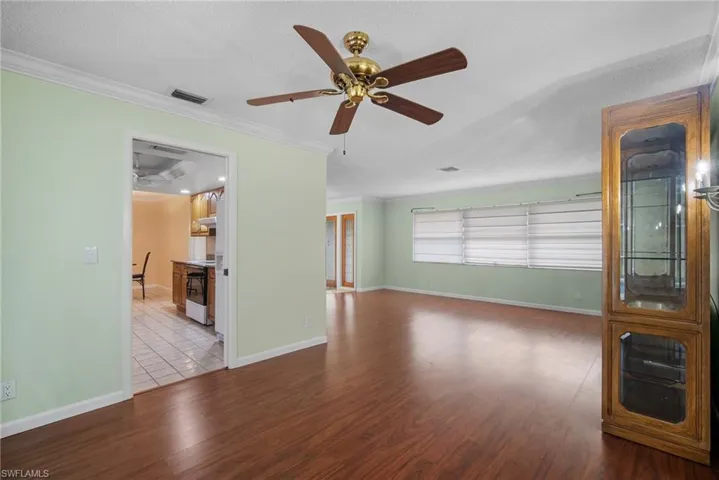 Unfurnished living room featuring ornamental molding, light hardwood / wood-style floors, a textured ceiling, and ceiling fan