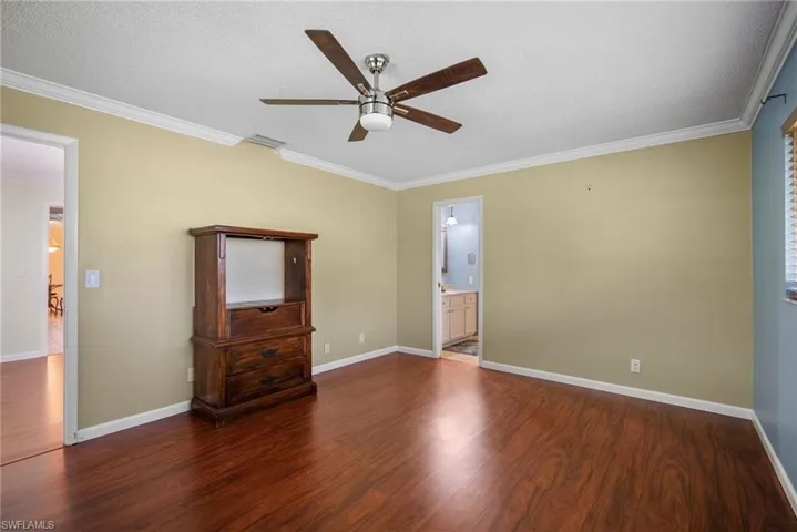 Empty room with ornamental molding, dark wood-type flooring, a textured ceiling, and ceiling fan