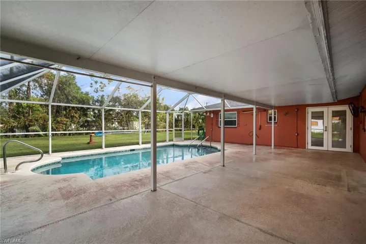 View of pool featuring glass enclosure, a patio area, and a lawn