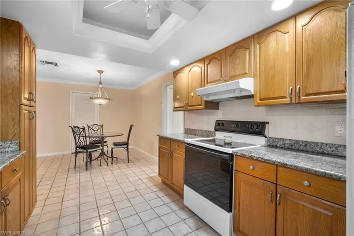Kitchen featuring decorative backsplash, light tile patterned floors, ornamental molding, electric range, and pendant lighting
