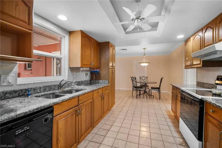 Kitchen with sink, light stone counters, white range with electric stovetop, ceiling fan, and dishwasher