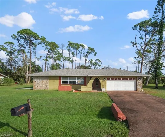 Single story home with a garage and a front lawn
