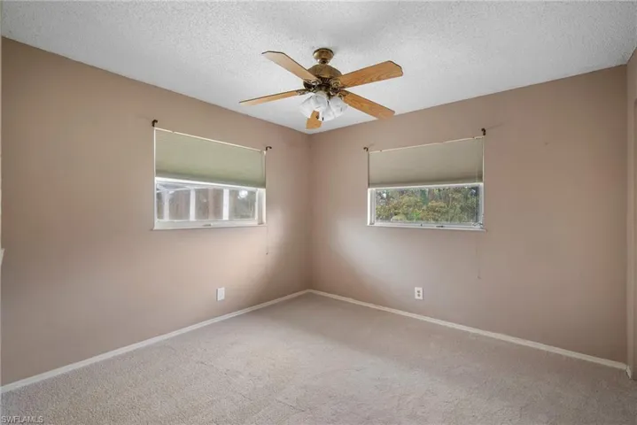 Carpeted empty room with ceiling fan and a textured ceiling