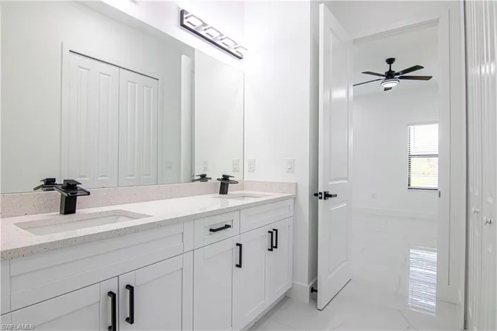 Bathroom with double vanity, ceiling fan, light marble finish flooring, and a closet