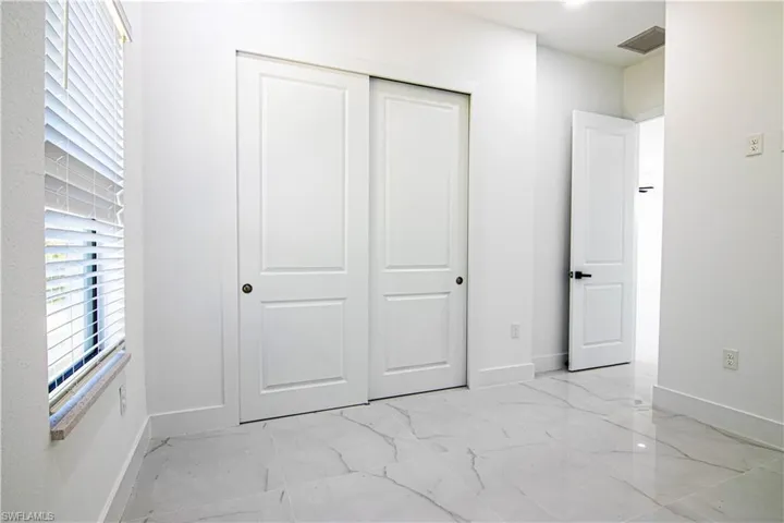 Unfurnished bedroom with a closet and light marble finish floors